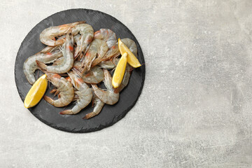 Fresh raw shrimps and lemon on grey table, top view. Space for text
