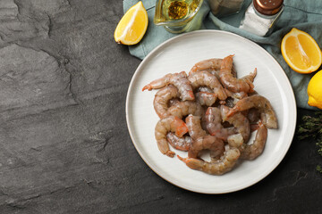 Fresh raw shrimps, spices and lemon wedges on grey table, flat lay. Space for text