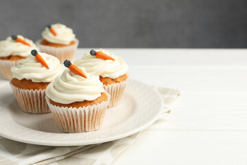 Tasty carrot muffins with cream on white wooden table, closeup. Space for text