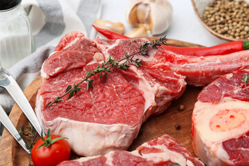 Pieces of raw beef, tomato and spices on white table, closeup