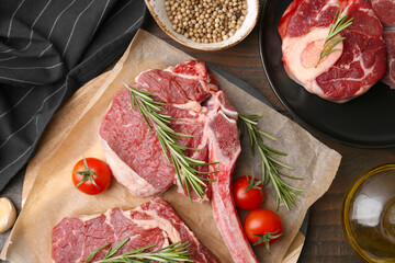 Pieces of raw beef, tomatoes and spices on wooden table, flat lay
