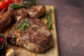 Pieces of delicious beef meat and spices on brown table, closeup. Space for text