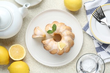 Flat lay composition of delicious lemon cake with glaze and mint on light textured table