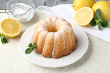 Delicious lemon cake with glaze, mint and citrus fruits on light textured table, closeup