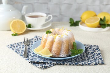 Delicious cake with lemon zest, powdered sugar and mint on light textured table