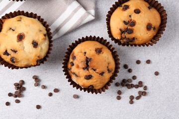 Delicious muffin with chocolate chips on light grey table, flat lay
