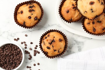 Delicious muffin with chocolate chips on white marble table, flat lay