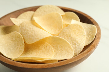 Tasty potato chips in bowl on white table, closeup