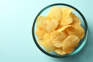 Tasty potato chips on light blue background, top view. Space for text