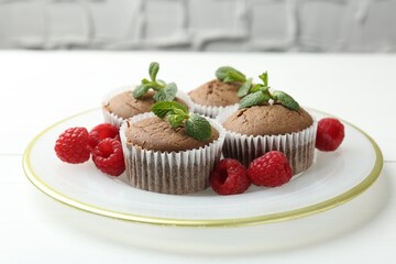 Delicious muffins with raspberries and mint on white table, closeup