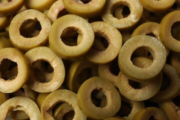Marinated green olive rings as background, top view