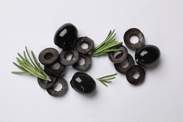 Marinated black olive rings, whole fruits and rosemary on white background, flat lay