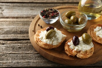 Delicious sandwiches with marinated olives, cream cheese and thyme on wooden table, closeup. Space for text