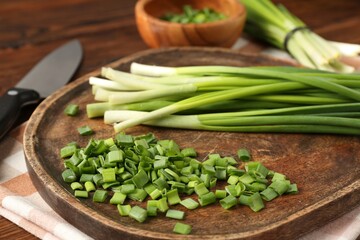 Fresh green onions and knife on table, closeup
