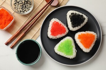 Tasty tobiko onigiri (Japanese rice balls) served on white marble table, flat lay