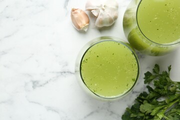 Healthy parsley smoothie, garlic and leaves on white marble table, flat lay. Space for text