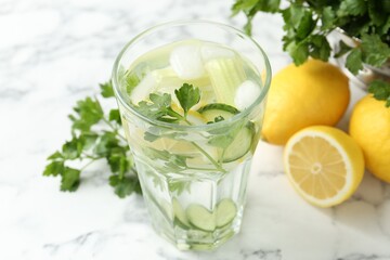 Healthy drink with parsley, cucumbers and lemons on white marble table, closeup
