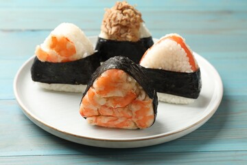 Tasty onigiri (Japanese rice balls) served on blue wooden table, closeup