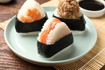 Tasty onigiri (Japanese rice balls) served on wooden table, closeup