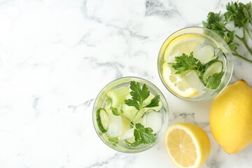 Healthy drink with parsley, cucumbers, lemons and celery on white marble table, flat lay. Space for text