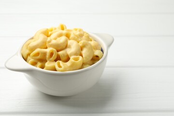 Delicious macaroni and cheese on white wooden table, closeup. Space for text