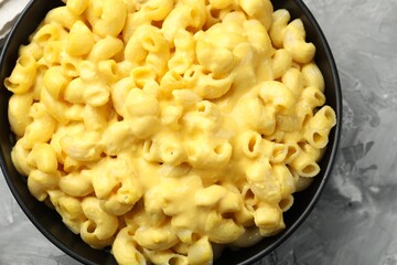 Delicious pasta with cheese sauce in bowl on grey table, top view