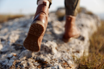 Person walking on top of a rock with brown boots on feet in outdoor adventure concept