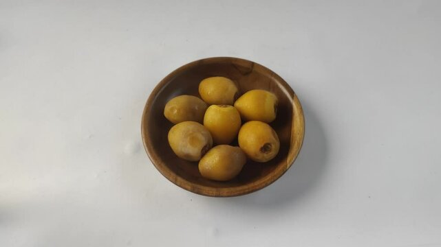 A group of fresh young dates or rutob dates or ruthob dates on a wooden plate with a white background.