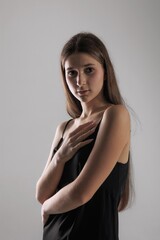 Young woman in black attire poses thoughtfully against a minimalist backdrop in a studio setting