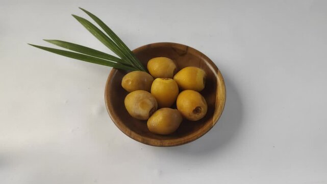 A group of fresh young dates or rutob dates or ruthob dates on a wooden plate with a white background.