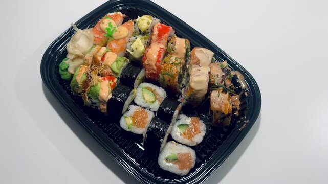 Sushi and rolls in plate. Close-up of sushi rolls on rectangle sushi plate. A set of fresh sushi rolls with salmon, avocado and black sesame seeds served on a plate with chopsticks. Japanese seafood 