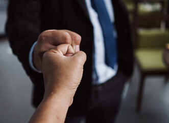 Fototapeta premium Close-up of two business professionals giving a fist bump, symbolizing teamwork, success, and motivation. Perfect for concepts of partnership, collaboration, and corporate culture.