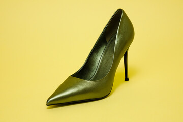 Green high hill shoe against yellow background.