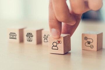 Seamless customer experience concept.  A close-up image of a hand selecting a wooden block with a customer icon and heart symbol, representing customer satisfaction, customer experience and engagement