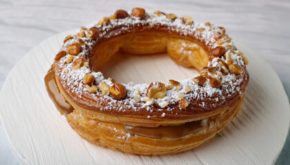 Paris-Brest with Hazelnut Cream – A ring-shaped choux pastry filled with rich praline hazelnut cream. The top is dusted with powdered sugar and adorned with caramelized hazelnuts