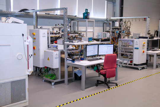 Industrial research lab with multi-screen data workstation, control panels, and testing infrastructure for precision monitoring and smart product engineering workflows