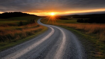 Fototapeta premium Winding country road at sunset. A gravel path curves through a grassy landscape towards a golden sunset, casting a warm glow on the scene. Rolling hills and distant trees frame the vista