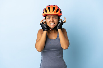 Young cyclist woman isolated on blue background frustrated and covering ears