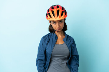 Young cyclist woman isolated on blue background with sad expression