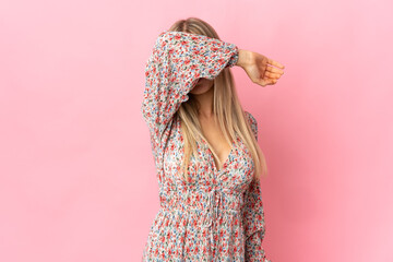 Young blonde woman isolated on pink background covering eyes by hands