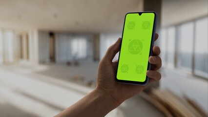 GREEN SCREEN CHROMA KEY A hand holding a smartphone with a green screen inside a renovated apartment
