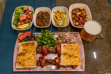 Meal in Turkey - dish of Adana kebab with side dishes and ayran drink