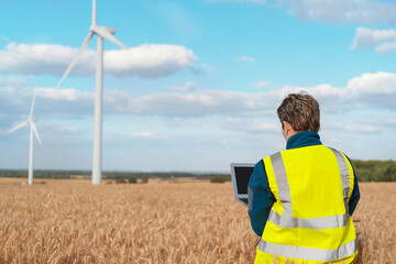 Woman technician monitors wind turbine performance in field during