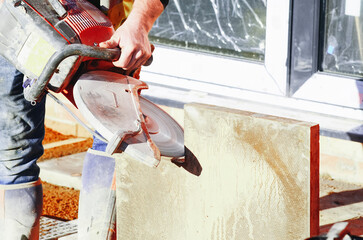 Worker cuts through concrete paving slab with power saw 