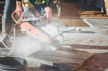 Constructing new patio with concrete saw on property with workers and materials present