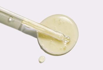 Liquid yellow gel or serum with pipette dropper on grey isolated background