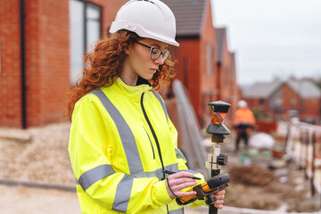 Femail building Engineer using surveying instrument on construction site 