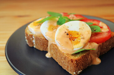 Closeup of Multi Grains Toast Open Faced Sandwich Topped with Hard Boiled Egg and Tomato