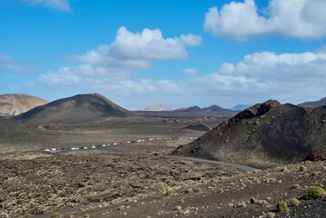Hike among volcanoes with volcanic relief in Timanfaya National Park in Lanzarote, Spain
