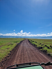 Fahrt mit dem Safari Fahrzeug über eine Schotterpiste neben einem See im berühmten Ngorongoro Krater in Tansania Afrika  (Hochformat)